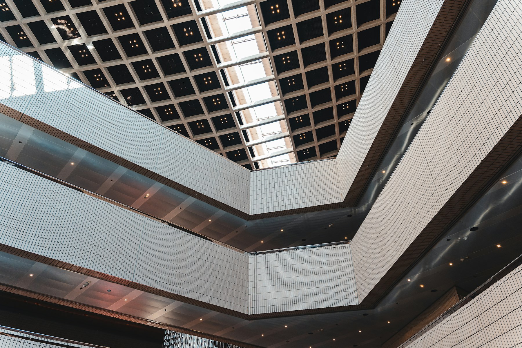 A geometric atrium ceiling with a repeating grid pattern, evoking an ongoing, orderly system.