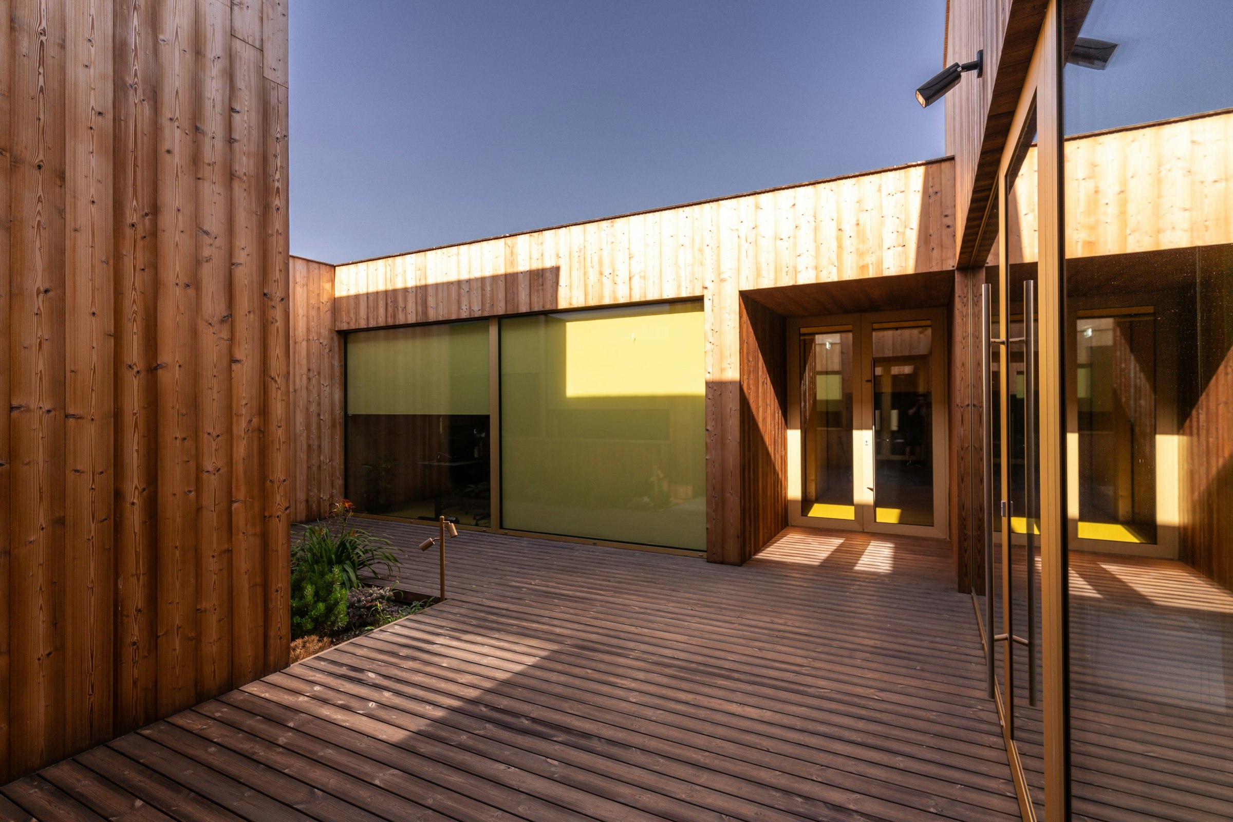 A wooden walkway leading to a building with glass doors.