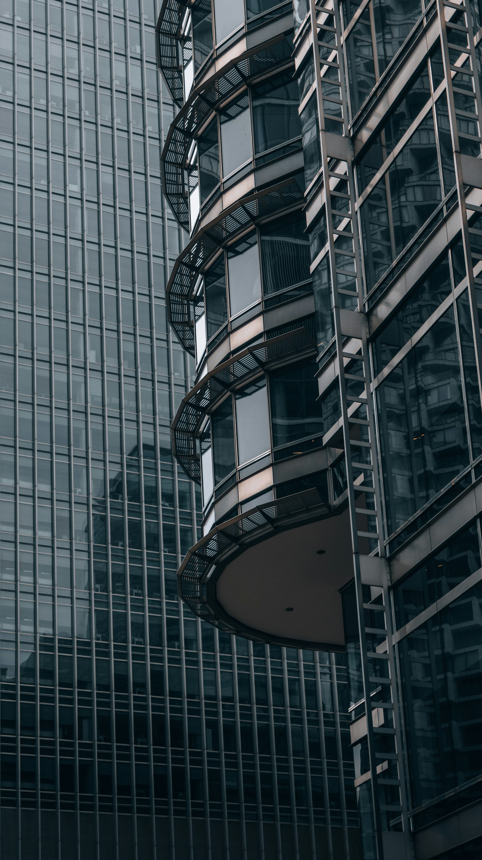 A close-up, low-angle view of a curved glass office tower facade.